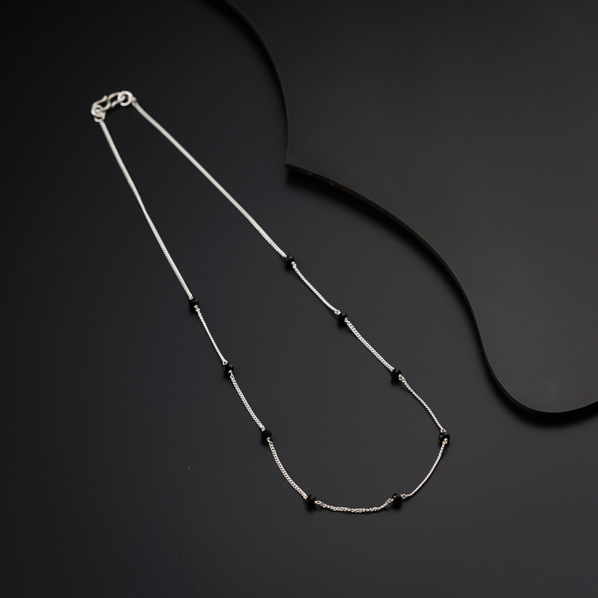 a black and white necklace on a black surface