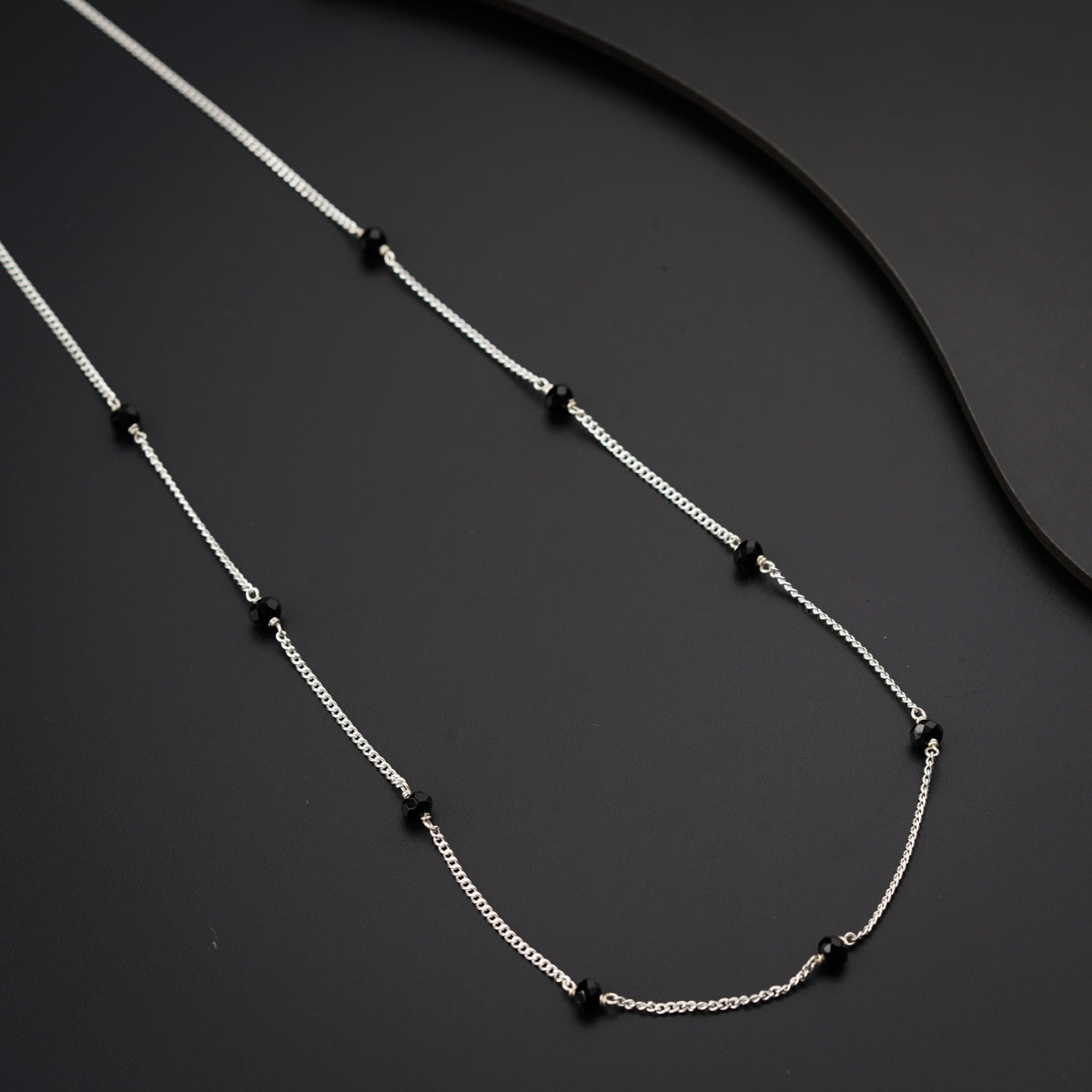 a black and white necklace on a black surface