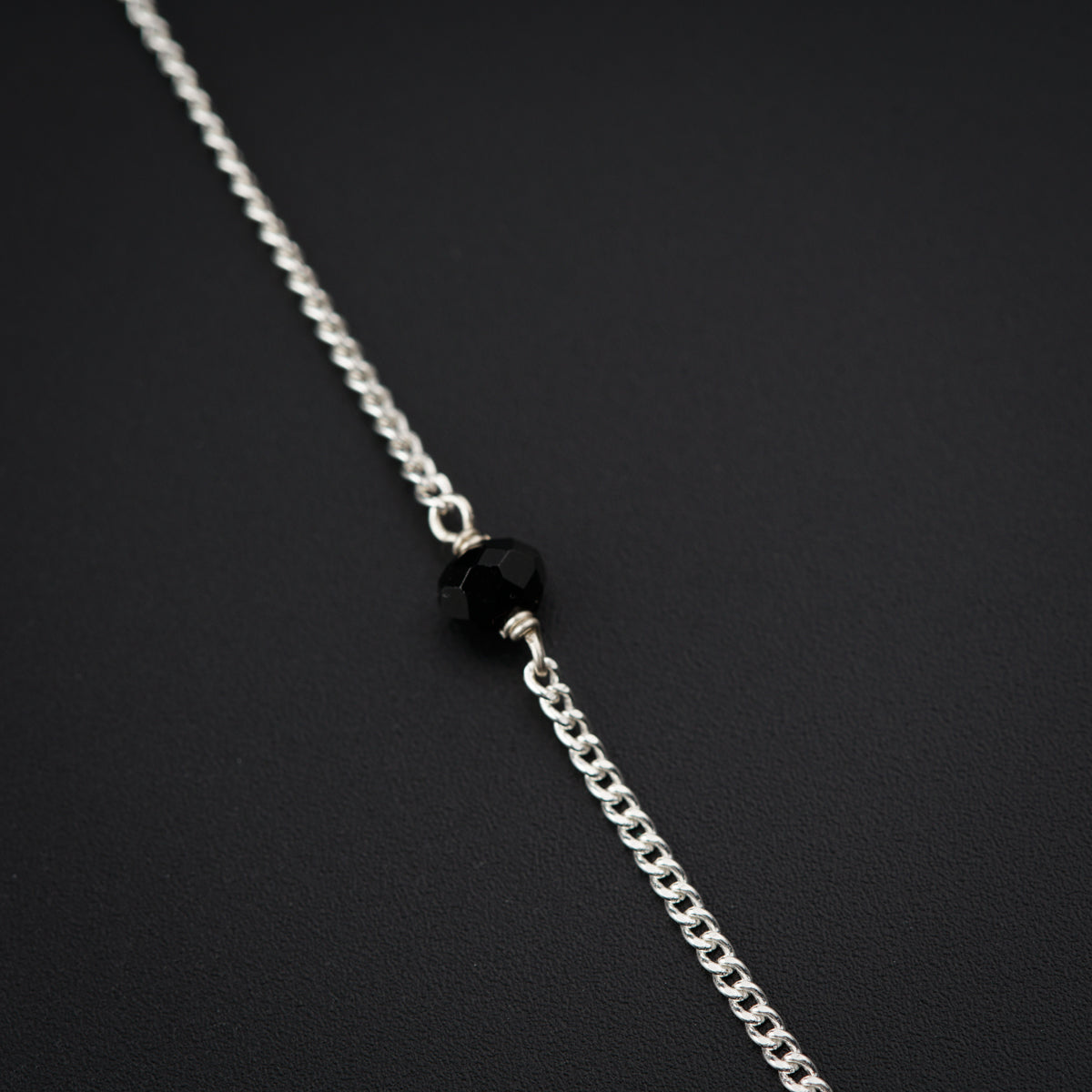 a silver chain with a black bead hanging from it