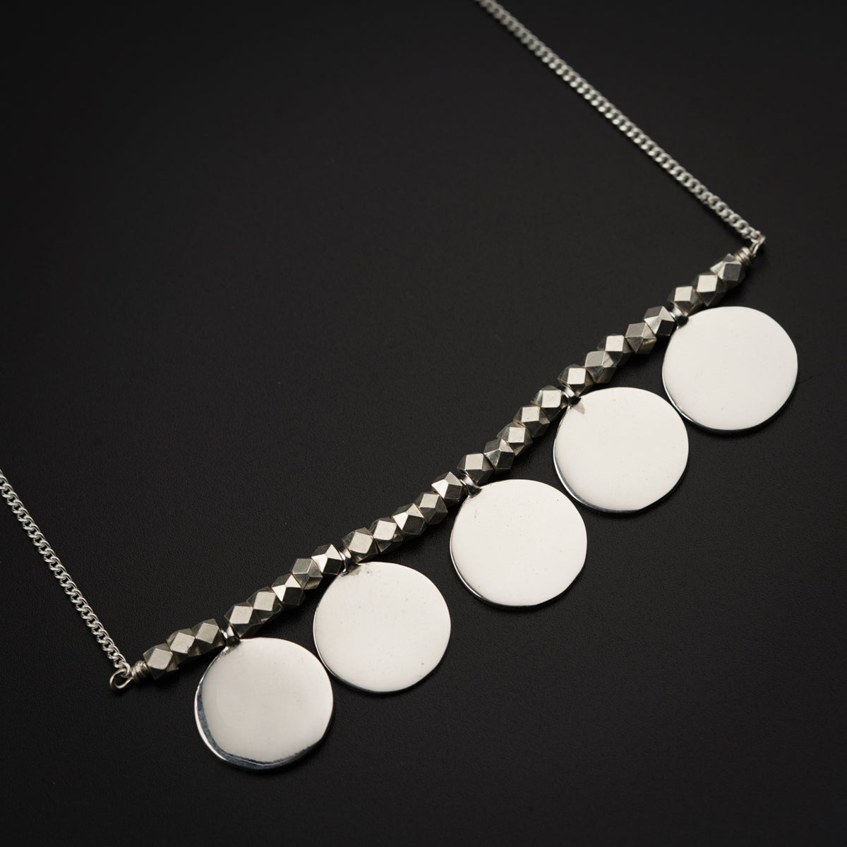 a silver necklace with five discs on it