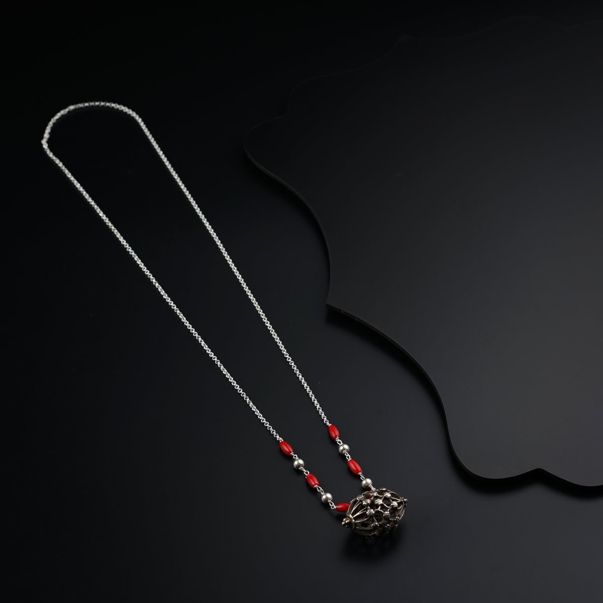 two necklaces on a black surface with a black background