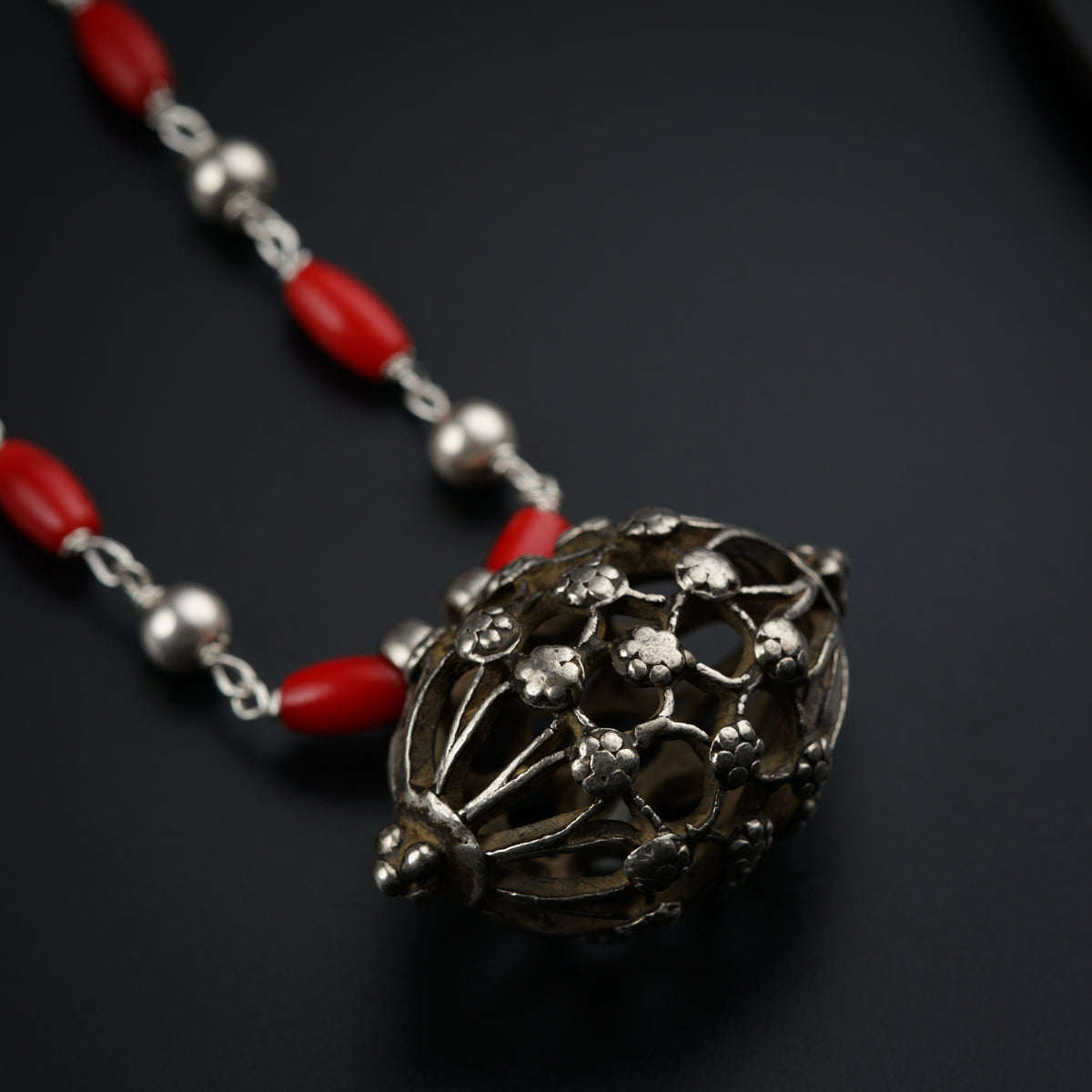a necklace with a red bead and a silver ball