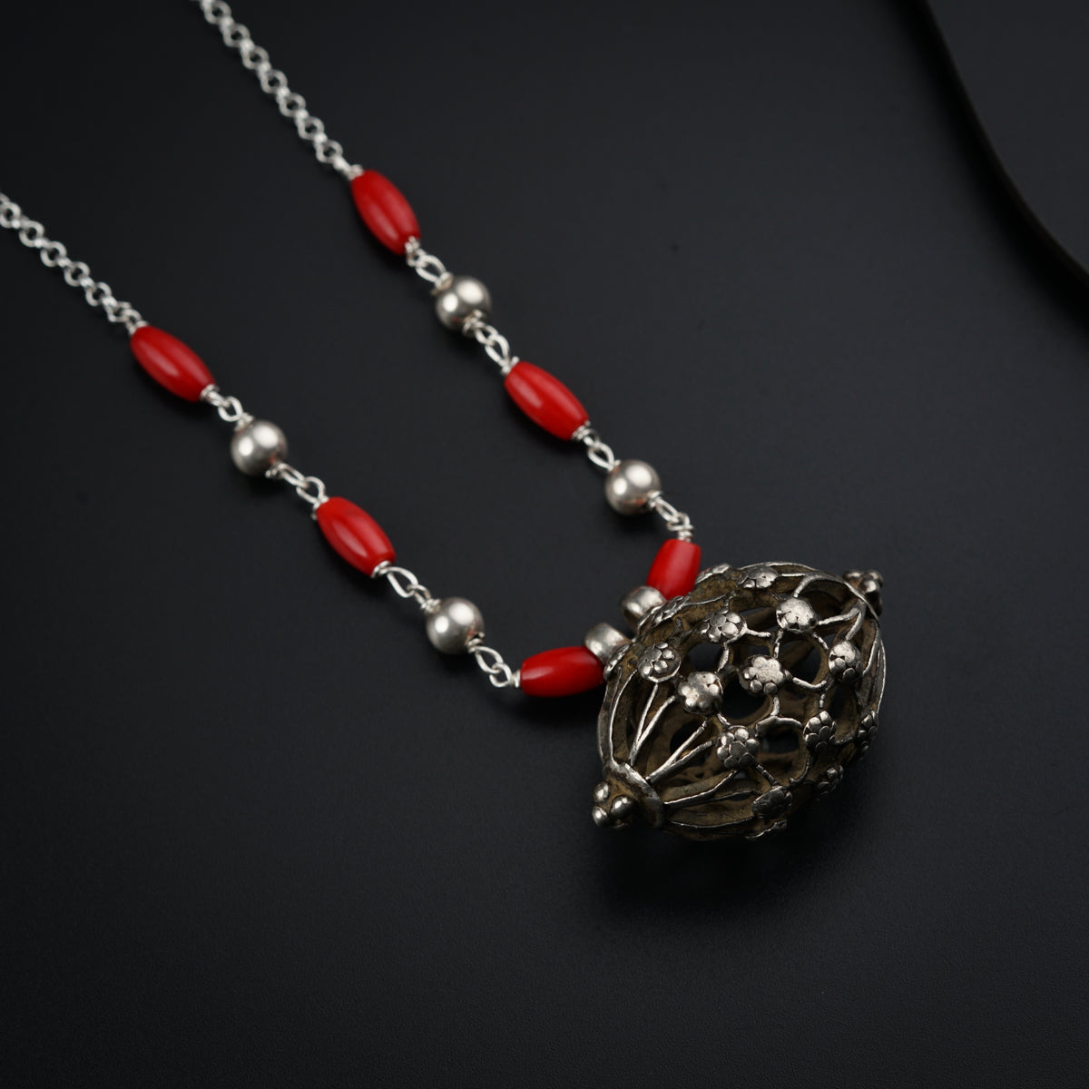 a necklace with a red bead and silver beads