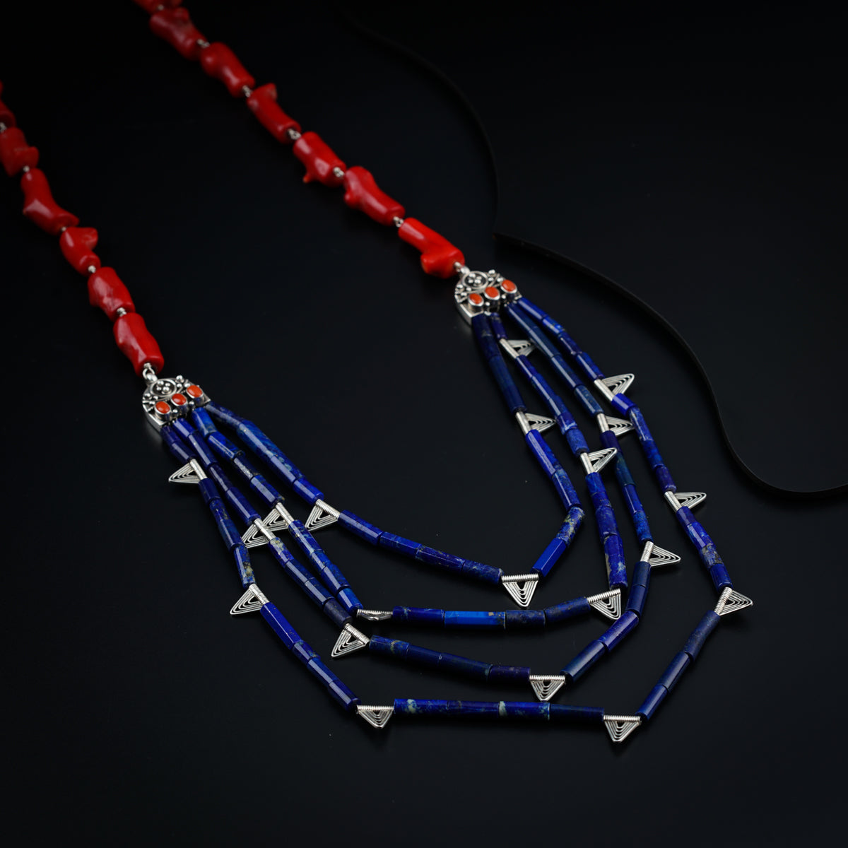 a blue and red necklace on a black surface