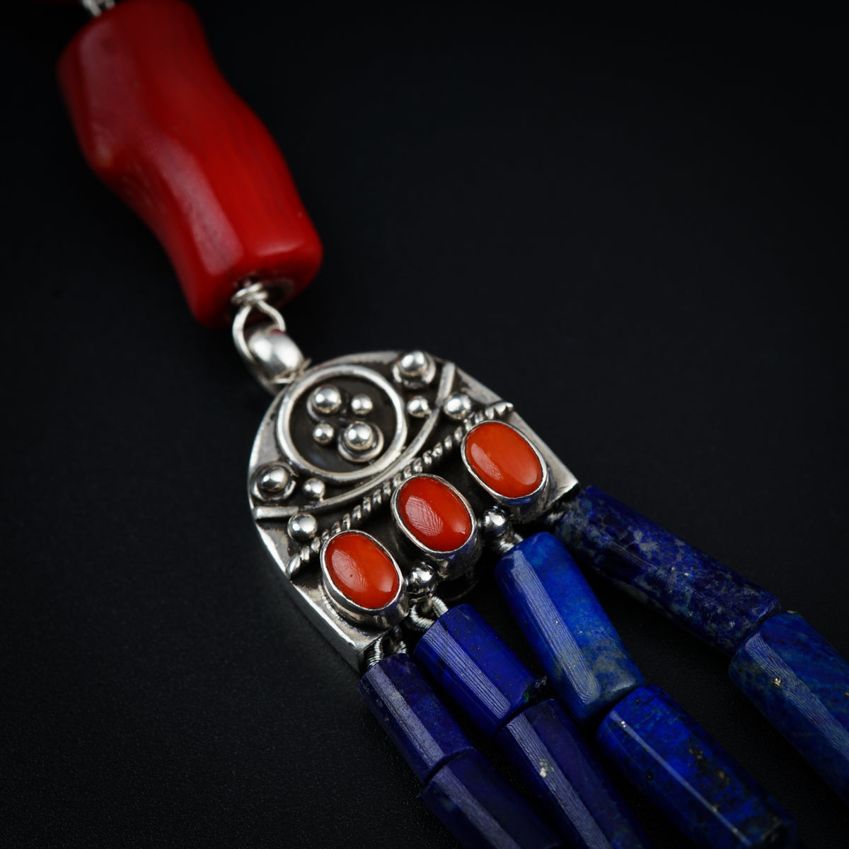 a blue and red necklace with a red bead