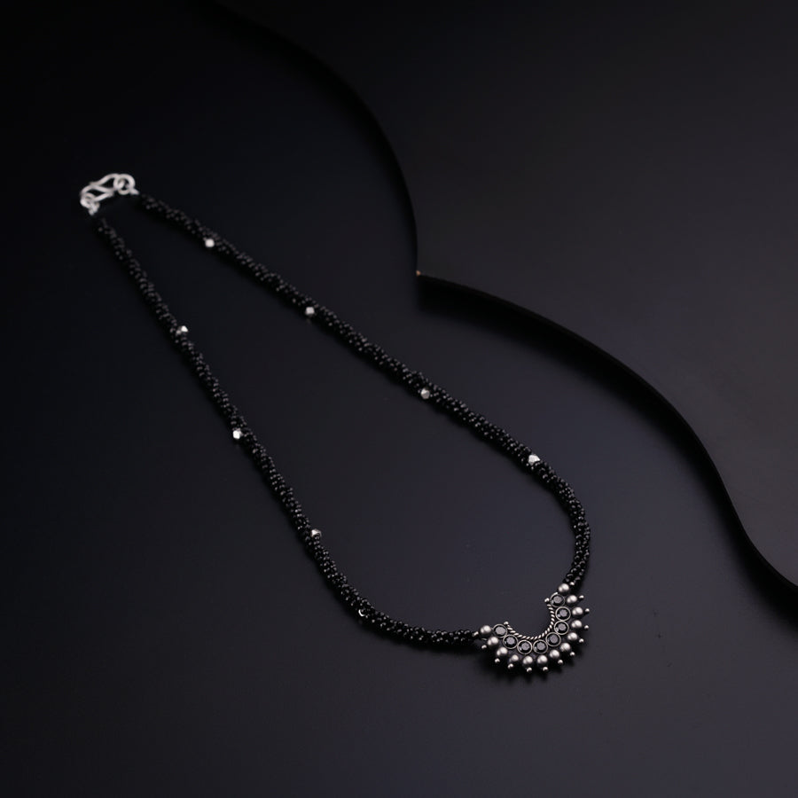 a black beaded necklace on a black surface