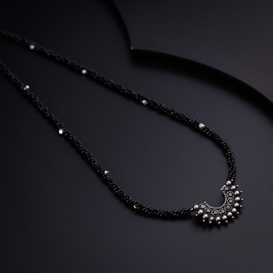 a black beaded necklace on a black surface