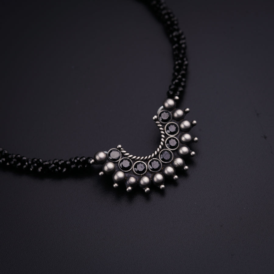 a black beaded necklace on a black surface