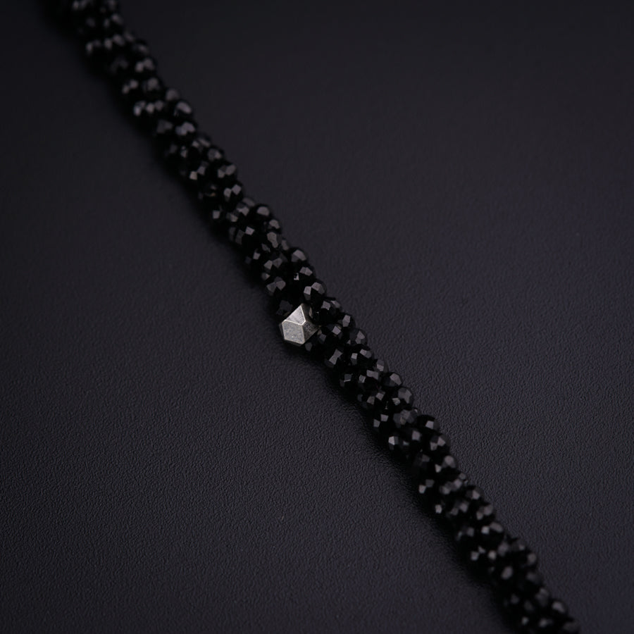 a close up of a black beaded necklace on a black surface