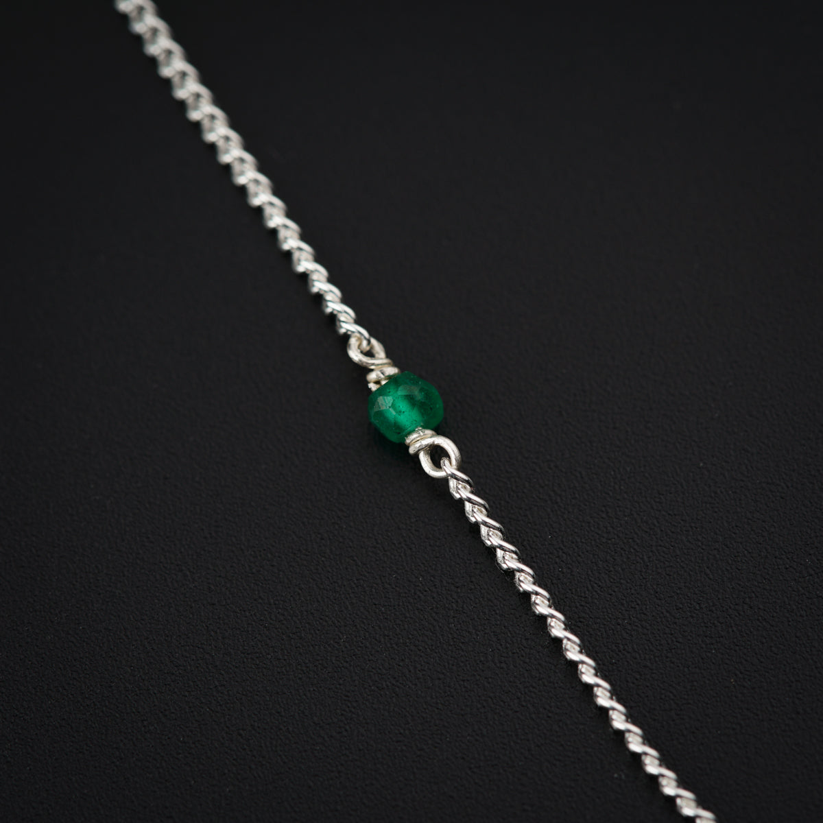 a silver chain with a green stone on it