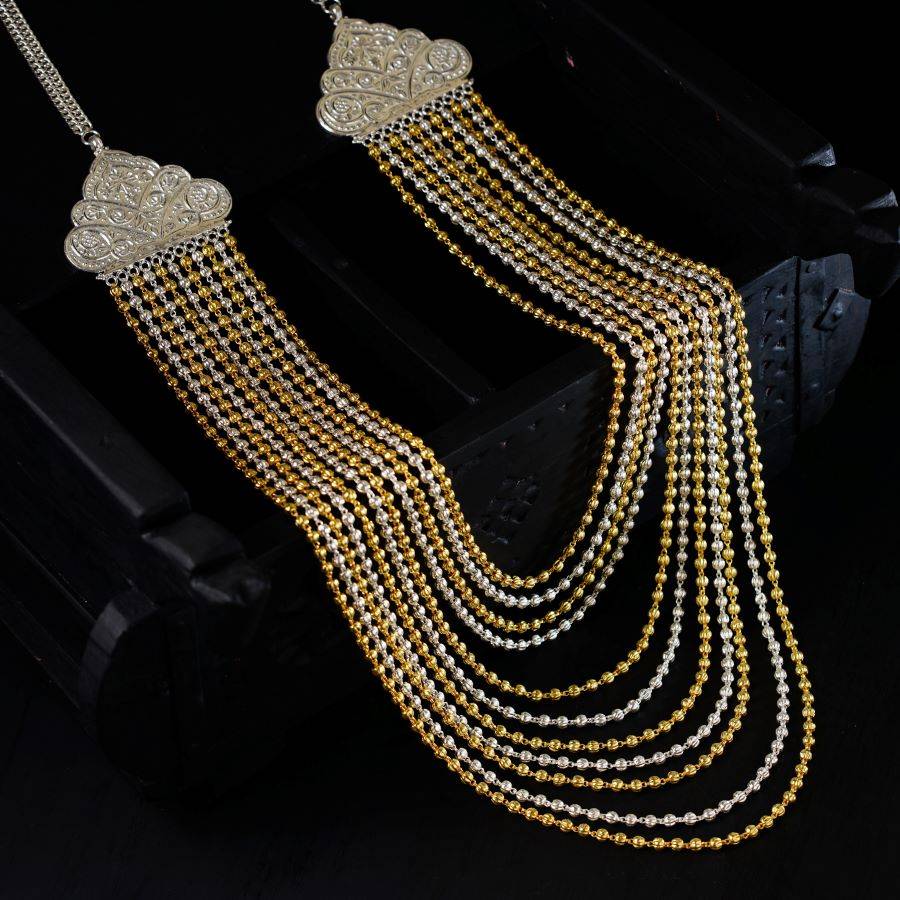 a pair of gold and silver necklaces on a black surface