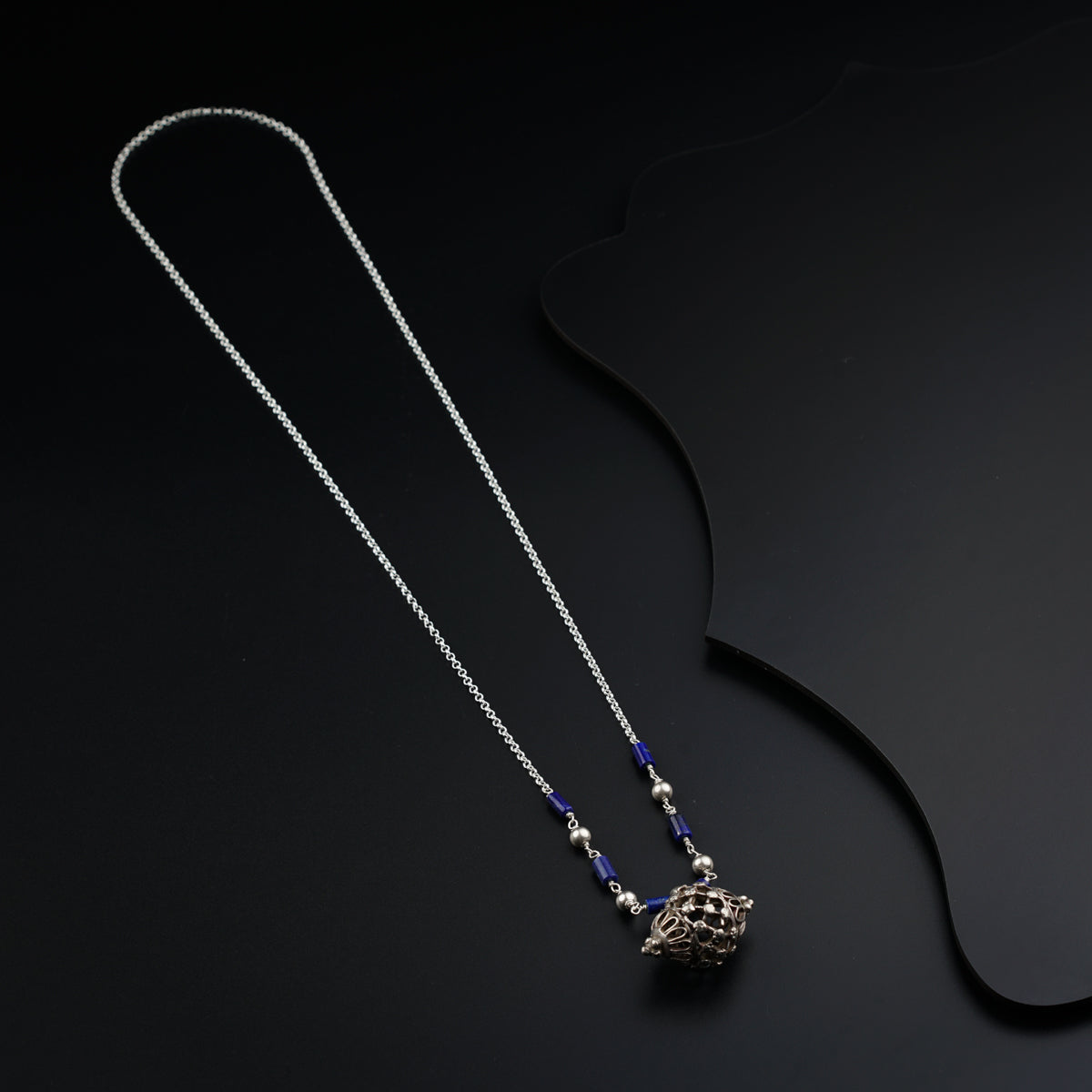 a silver necklace with a blue bead hanging from it