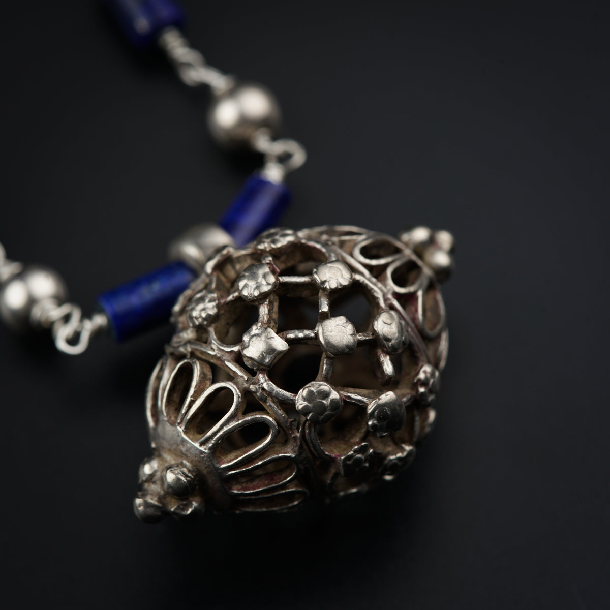 a silver and blue beaded necklace on a black surface