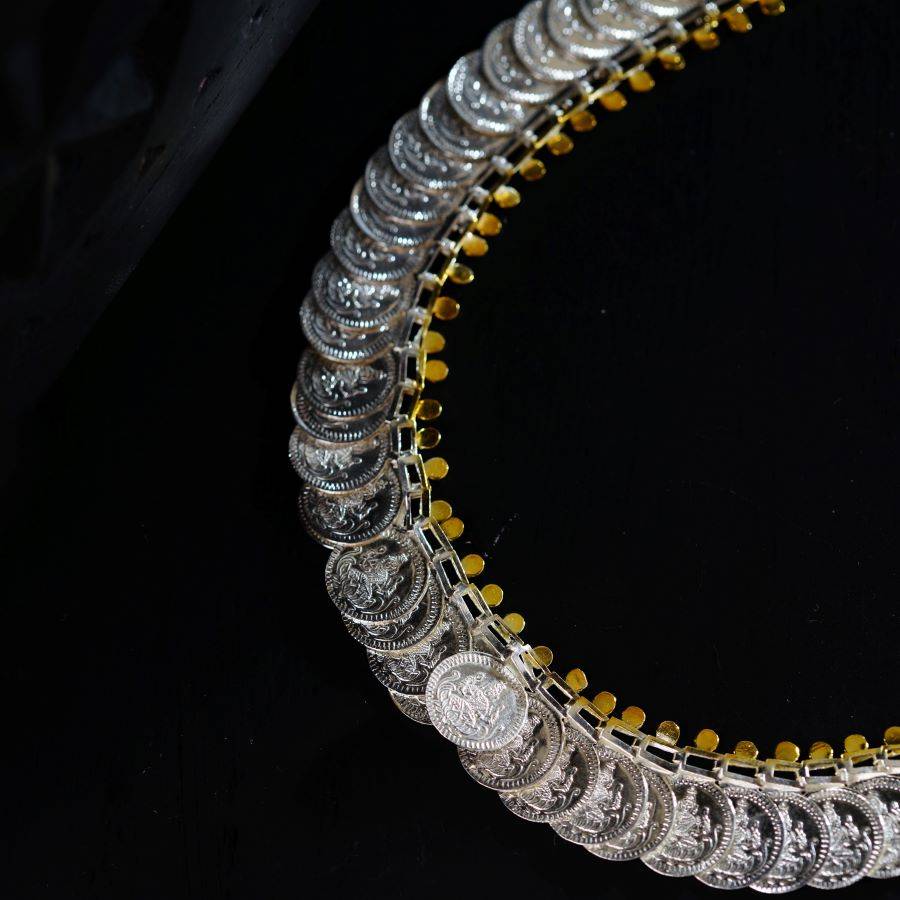 a silver and gold necklace on a black surface