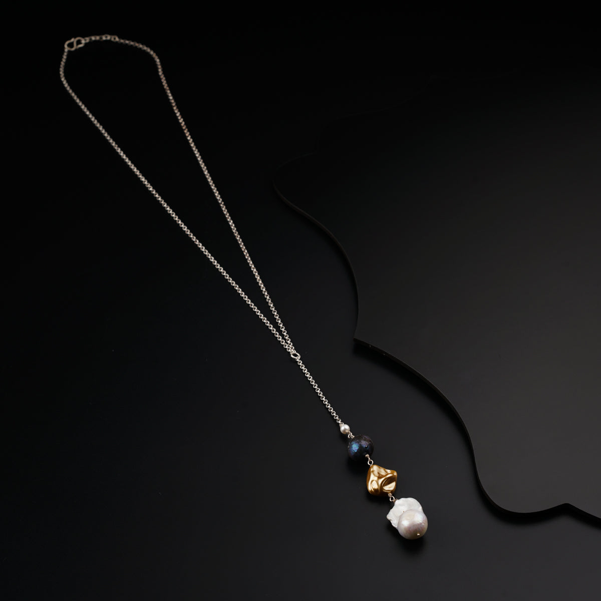 a necklace with a pearl and a gold leaf on it