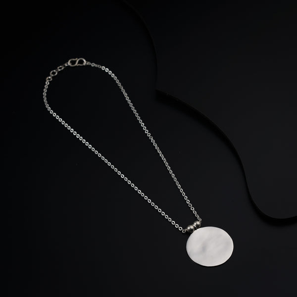 a white disc on a silver chain on a black background