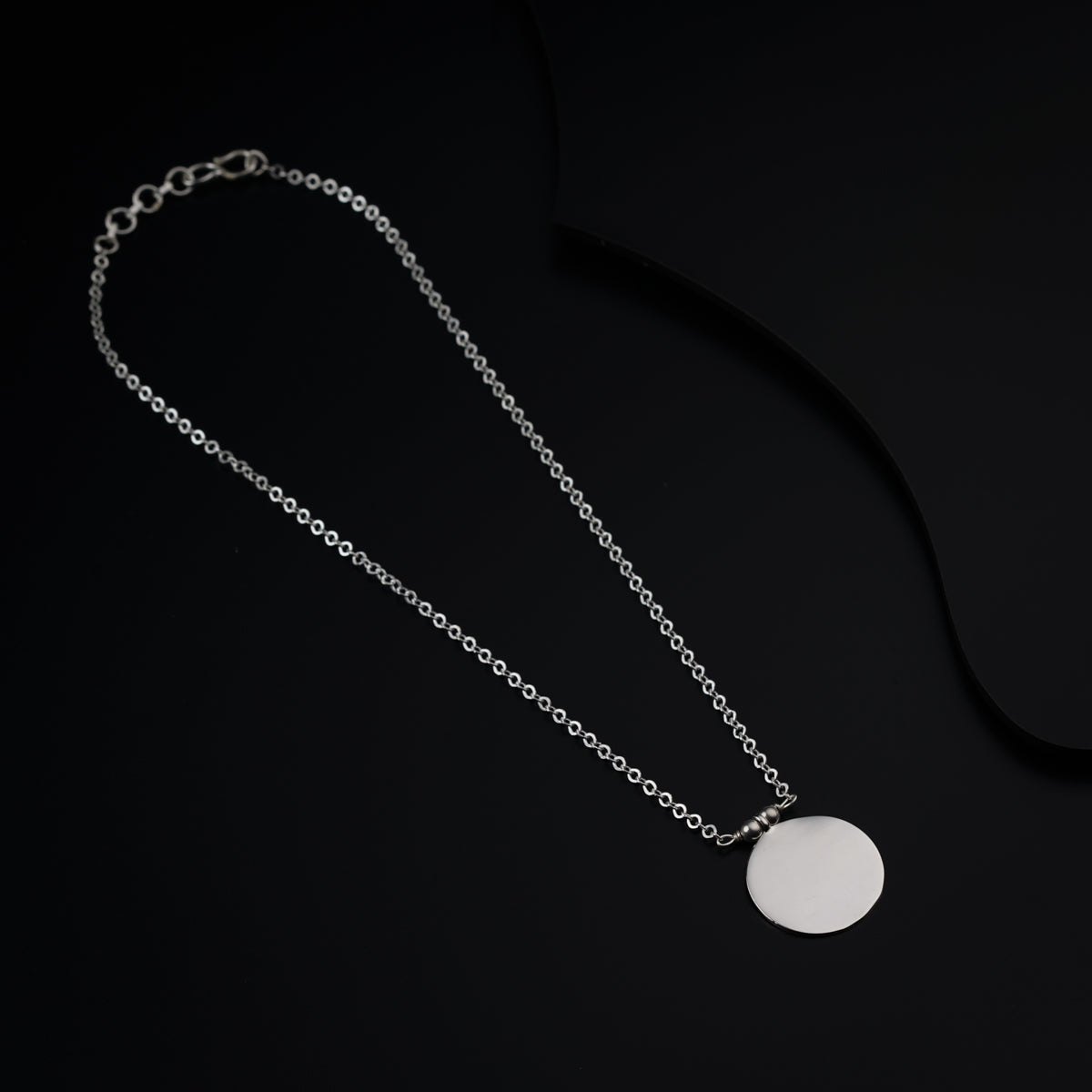 a necklace with a white disc on a black background