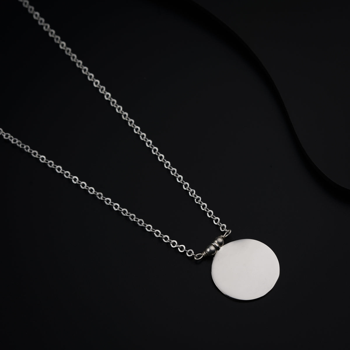 a necklace with a white disc on a black background