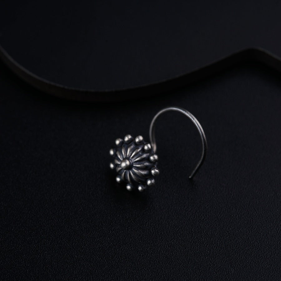 a pair of silver earrings on a black surface