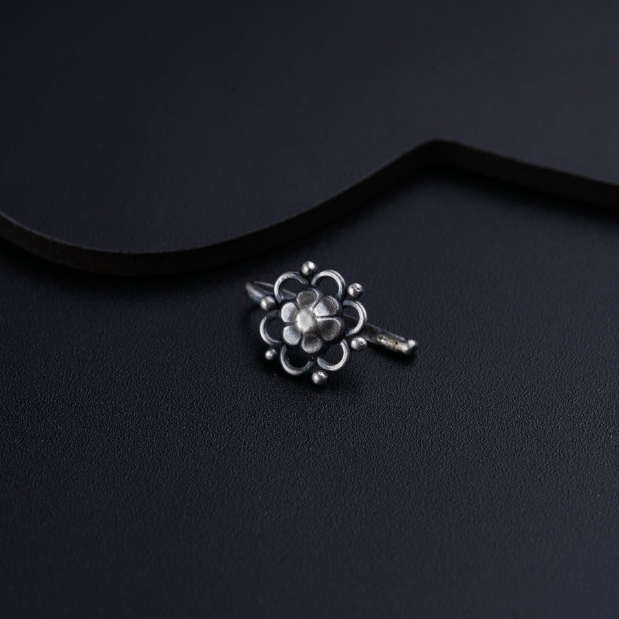 a silver key with a flower on it on a black surface