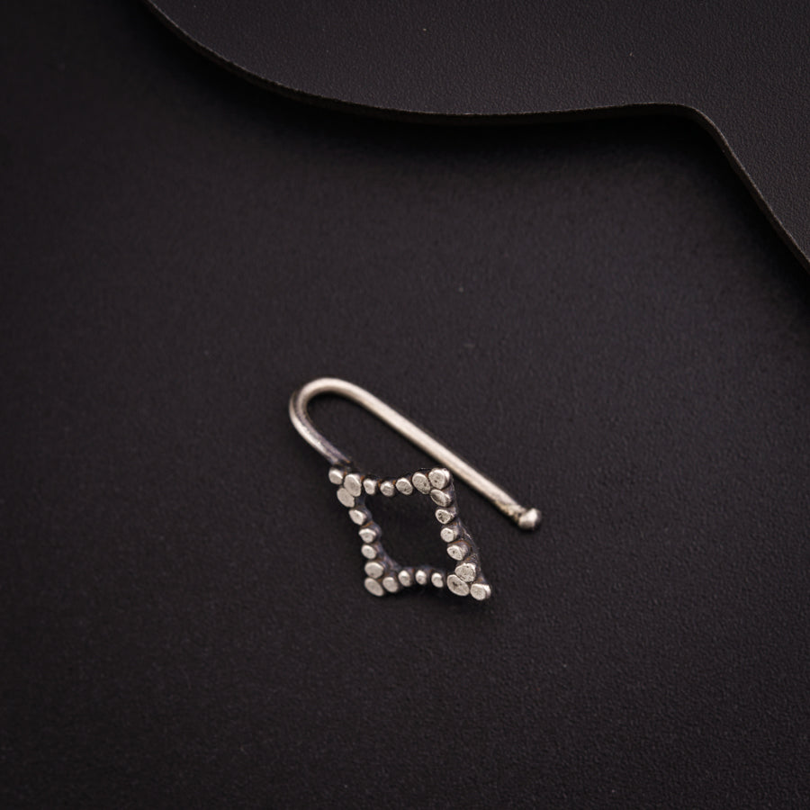 a pair of silver earrings sitting on top of a black surface
