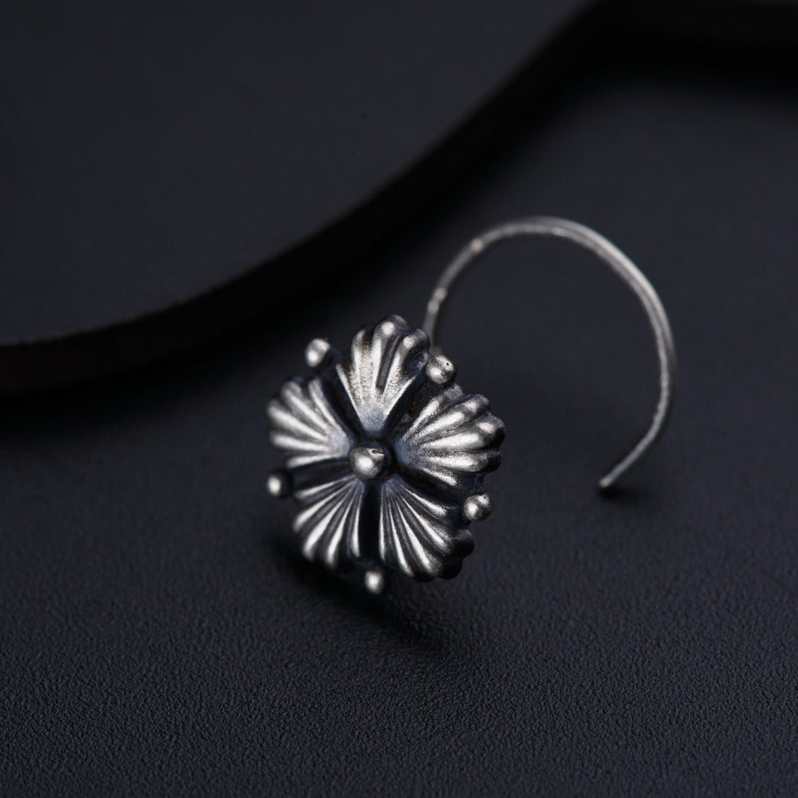 a pair of silver earrings sitting on top of a black surface