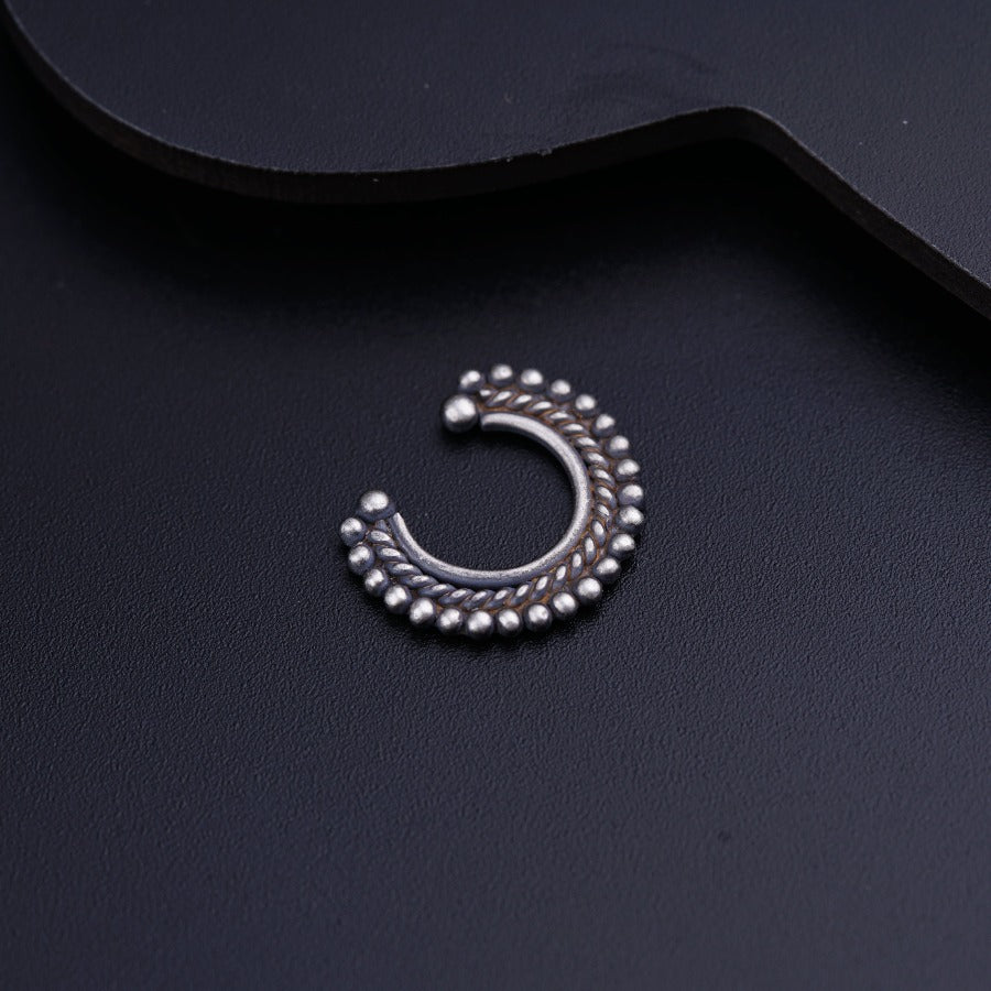 a pair of silver earrings sitting on top of a black surface