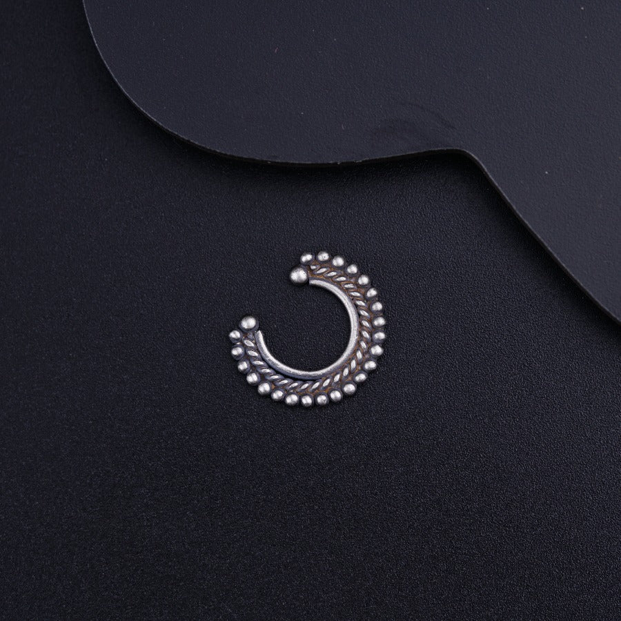 a pair of silver earrings sitting on top of a black surface