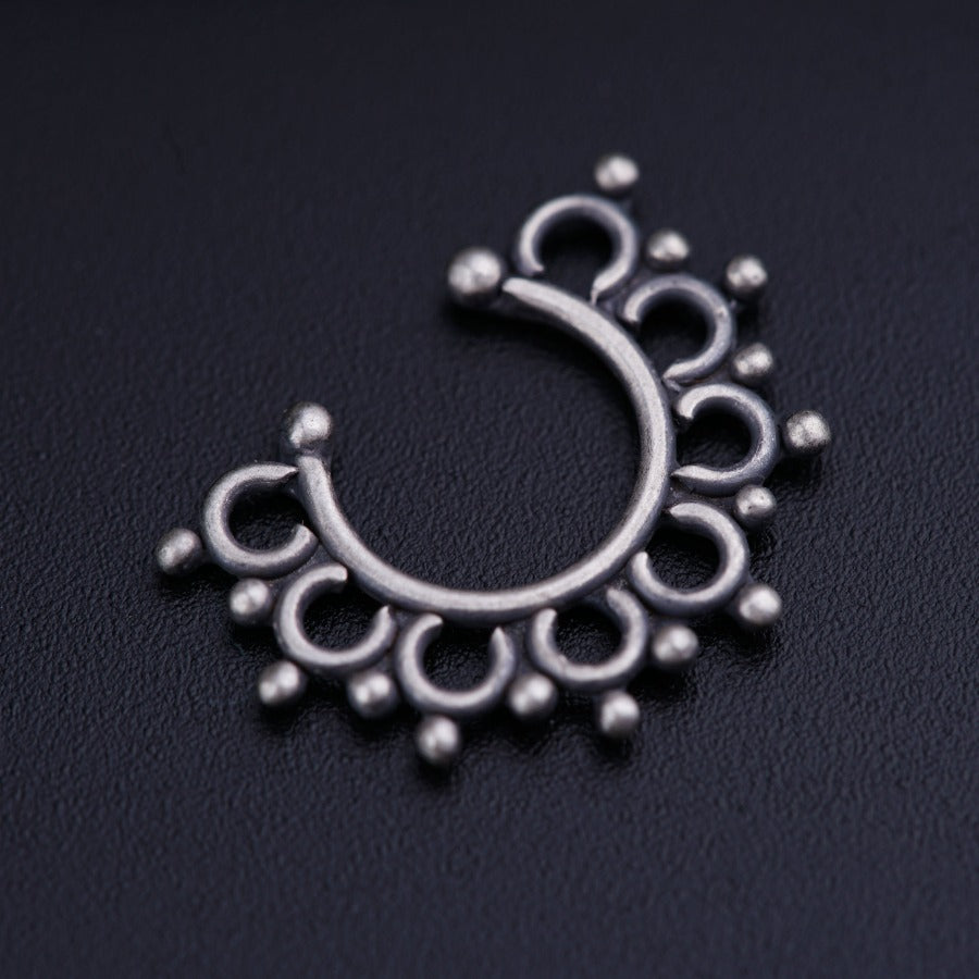 a silver nose ring on a black surface