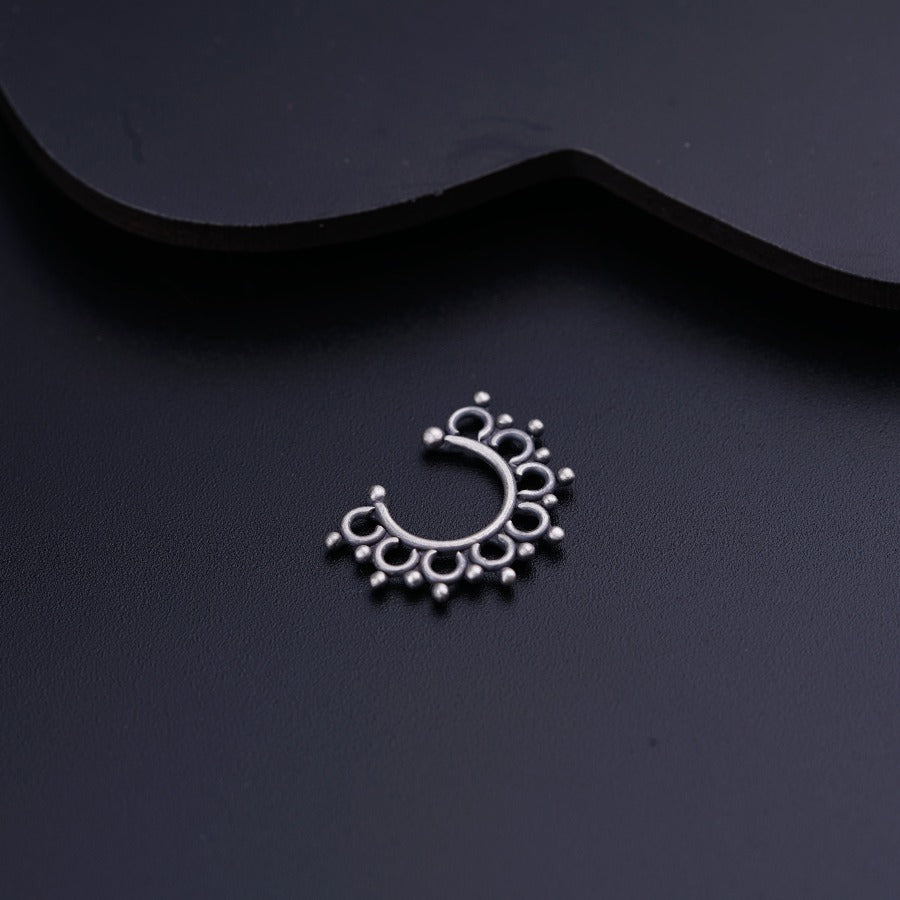 a black background with a silver nose ring