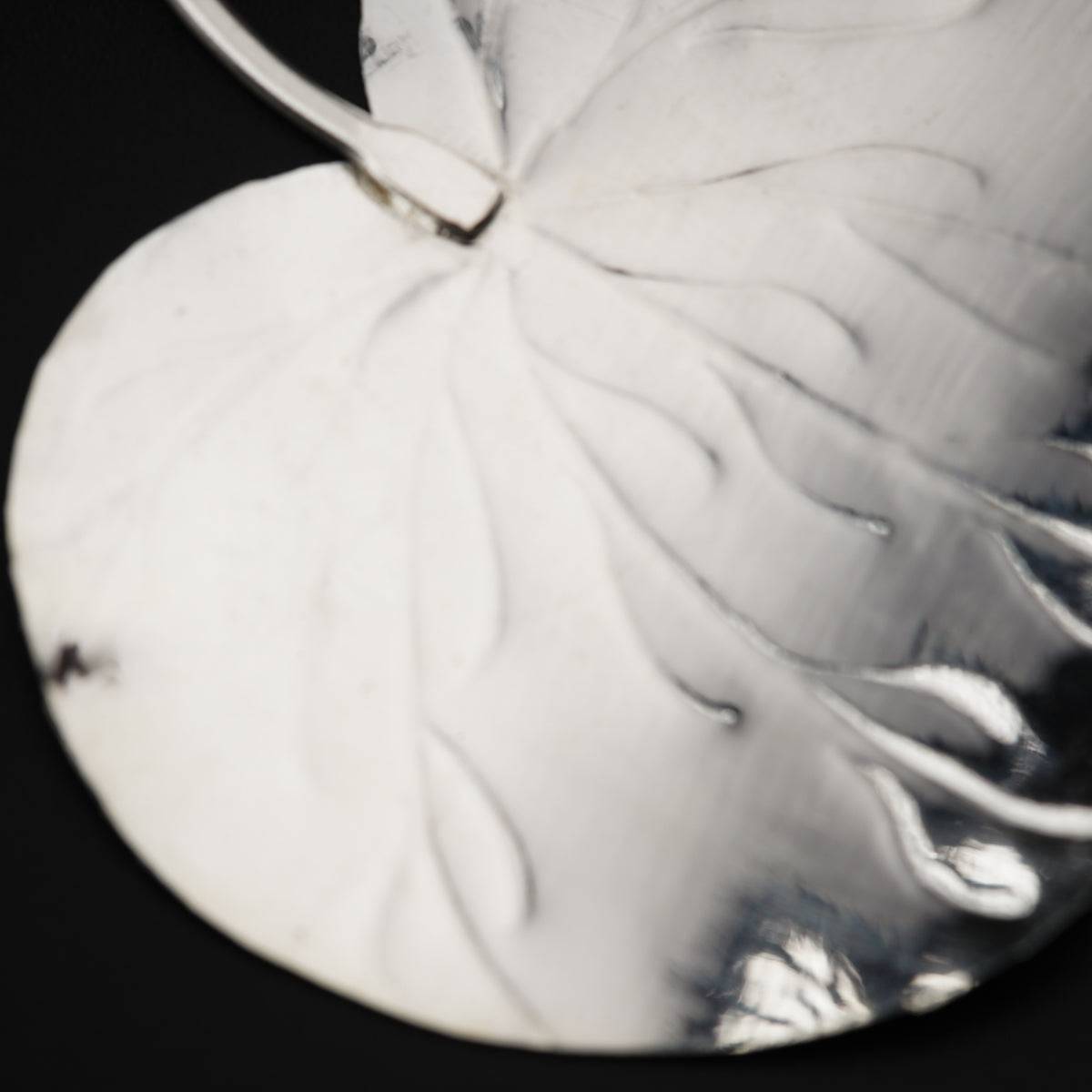 a metal disc with a leaf design on it