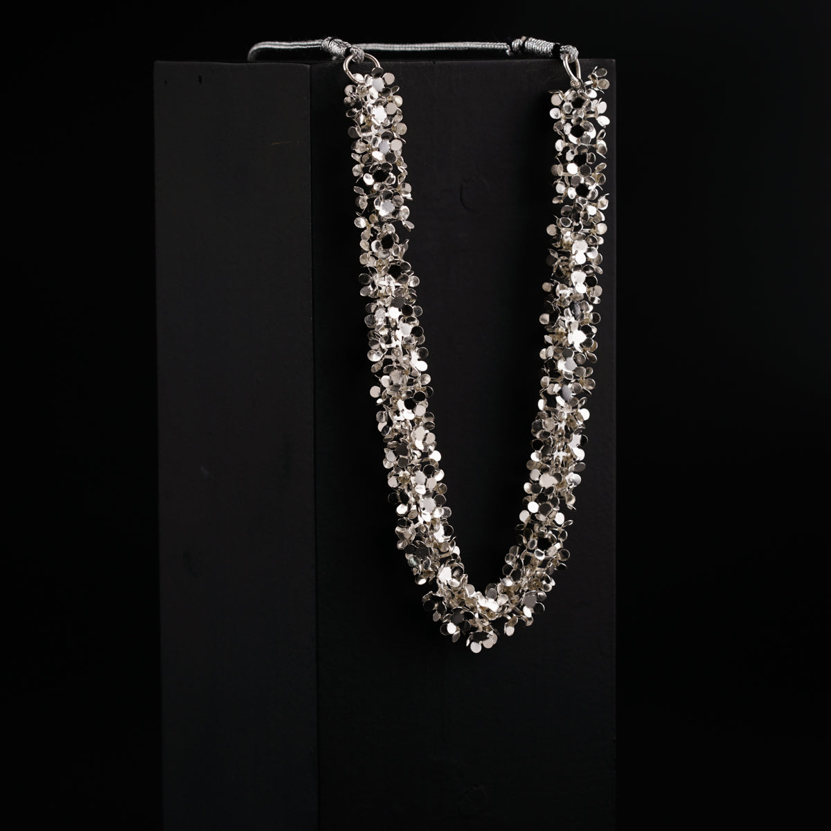 a necklace is displayed on a black stand