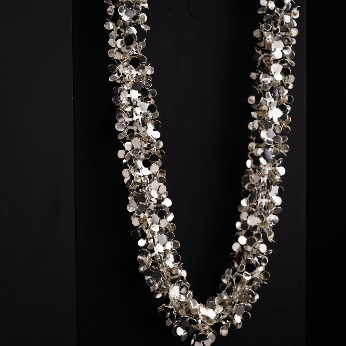 a long necklace with silver beads on a black background