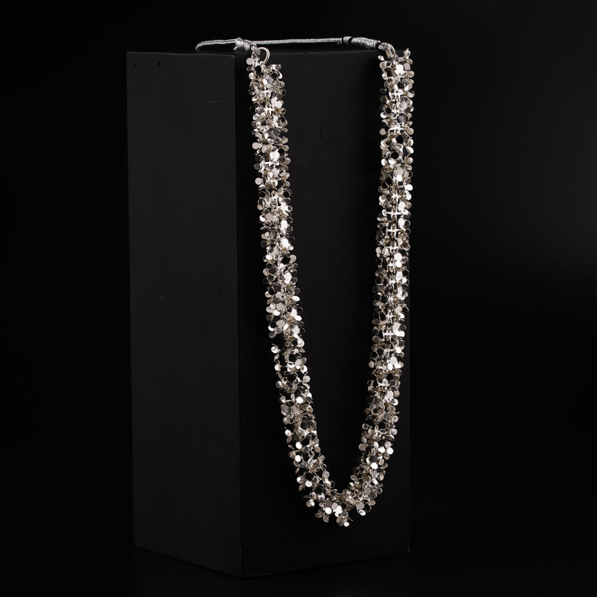 a long necklace is on display in a black box
