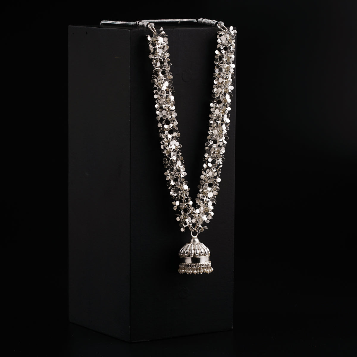 a silver necklace with a bell hanging from it