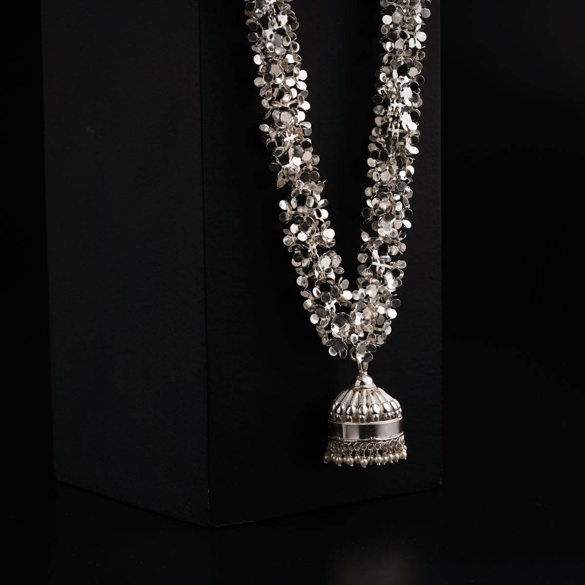 a necklace with a bell on a black background
