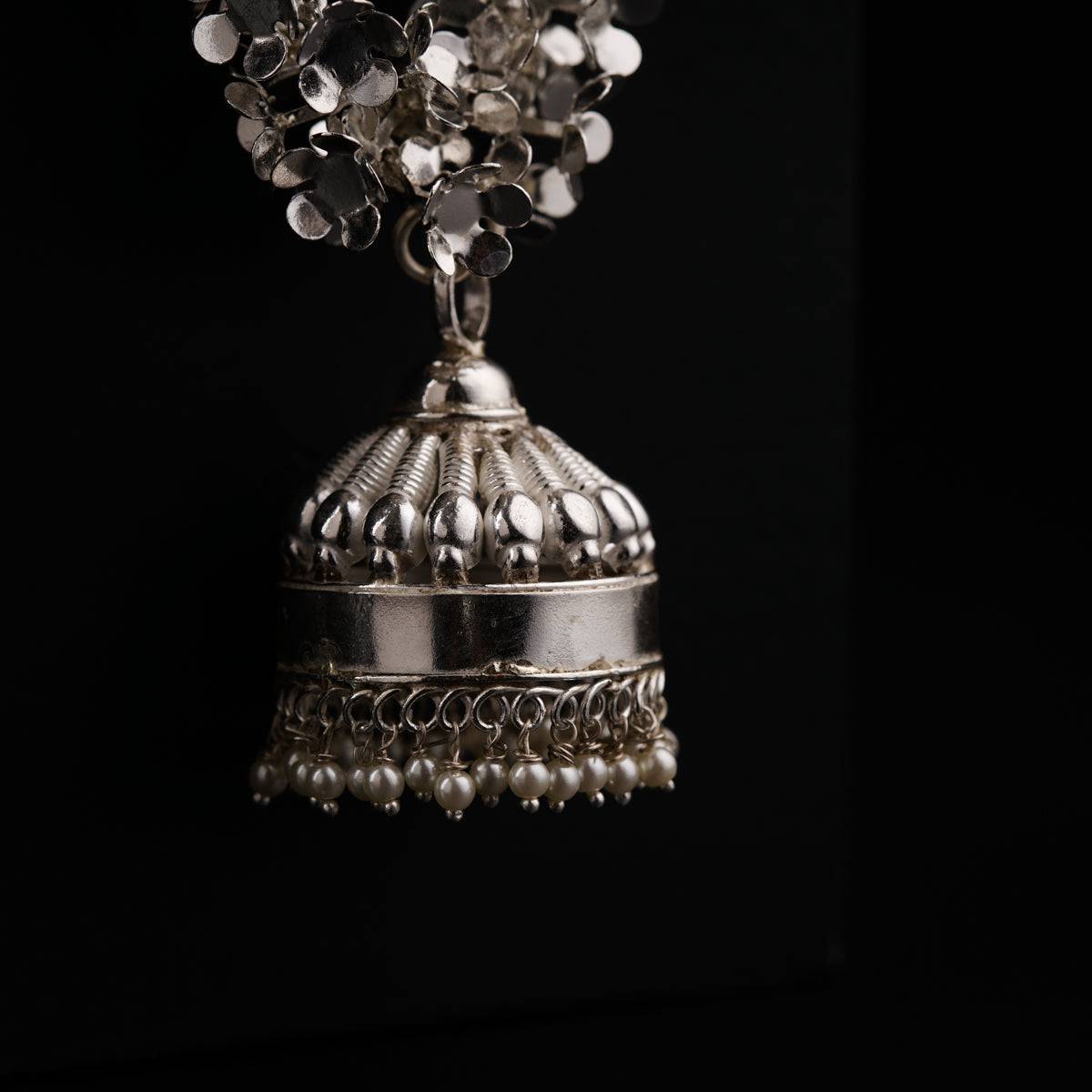 a silver bell with a bunch of beads on top of it