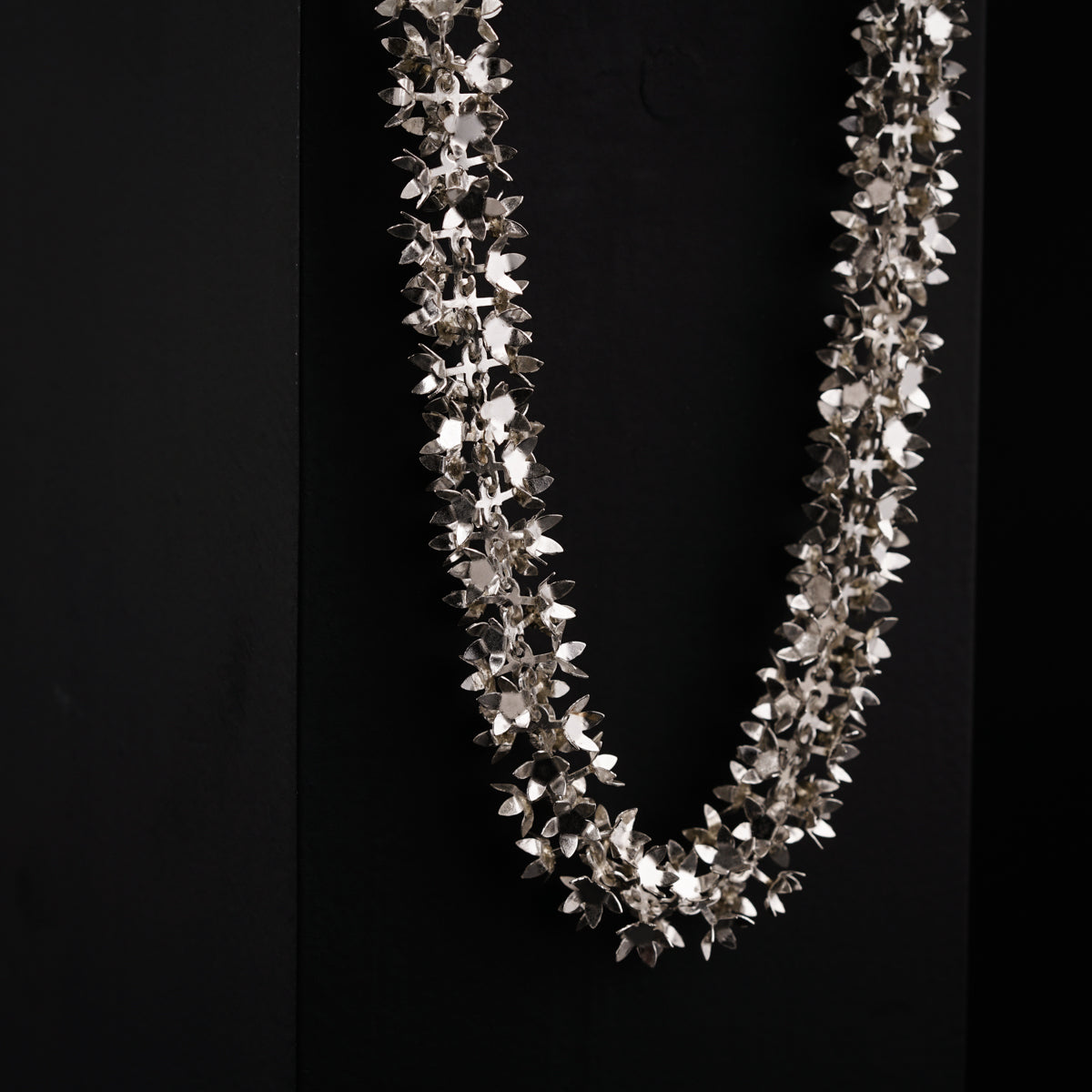 a necklace with silver flowers on a black background