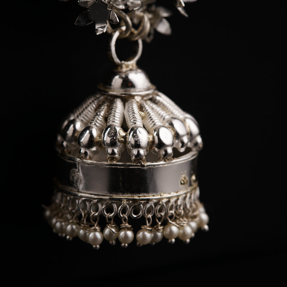 a silver bell with pearls hanging from it