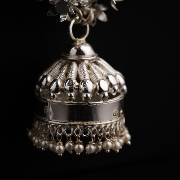 a silver bell with pearls hanging from it