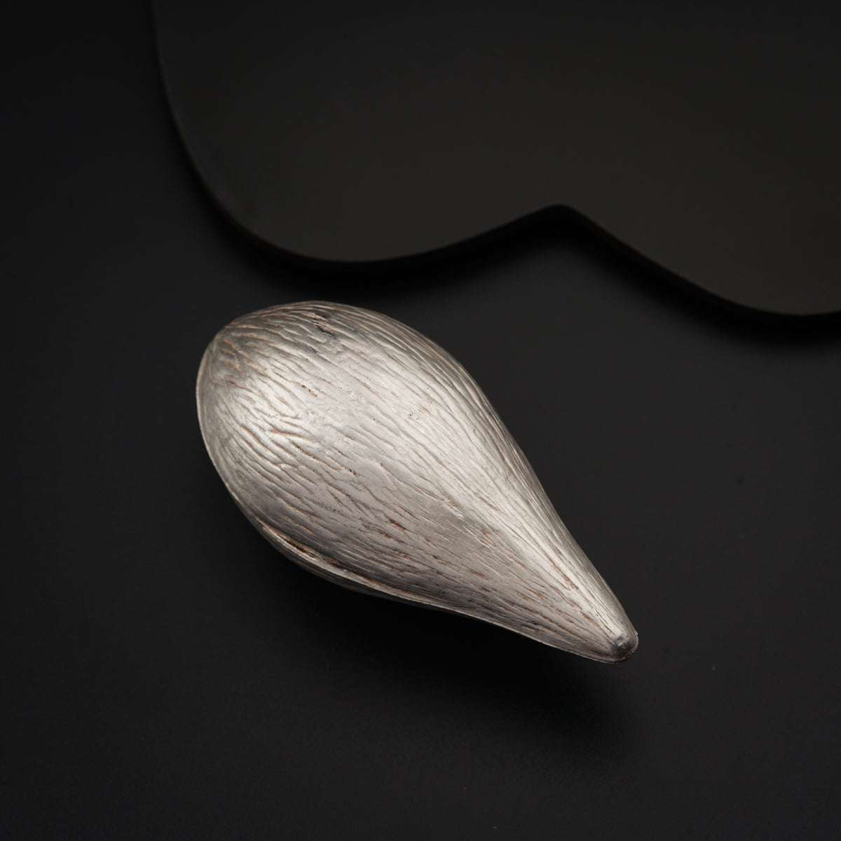 a metal object sitting on top of a black surface