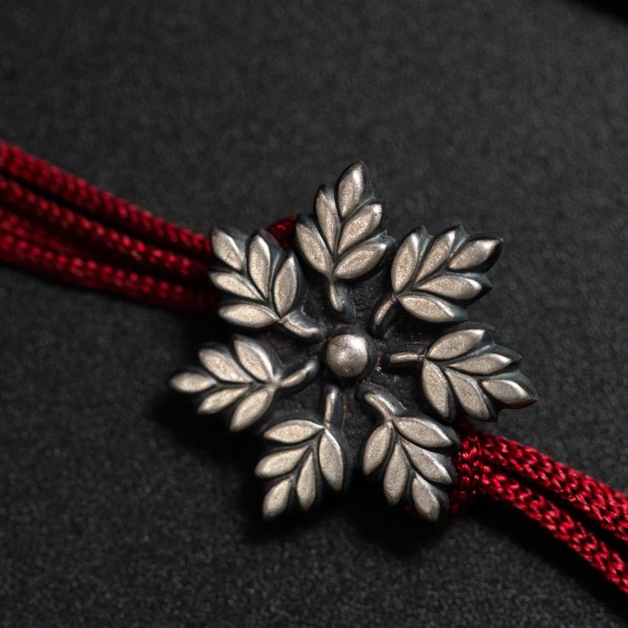 a silver flower on a red string