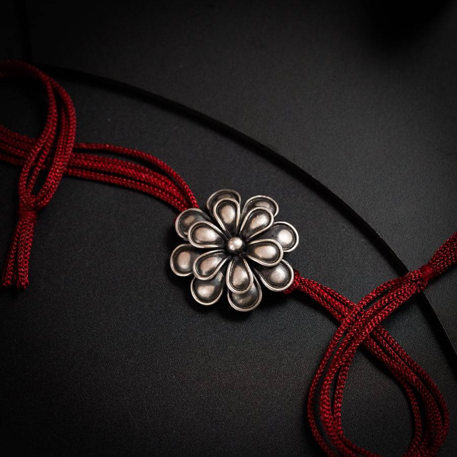 a red cord with a silver flower on it