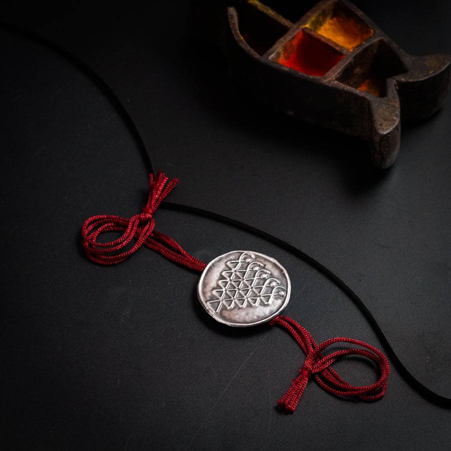 a red string with a silver coin on it