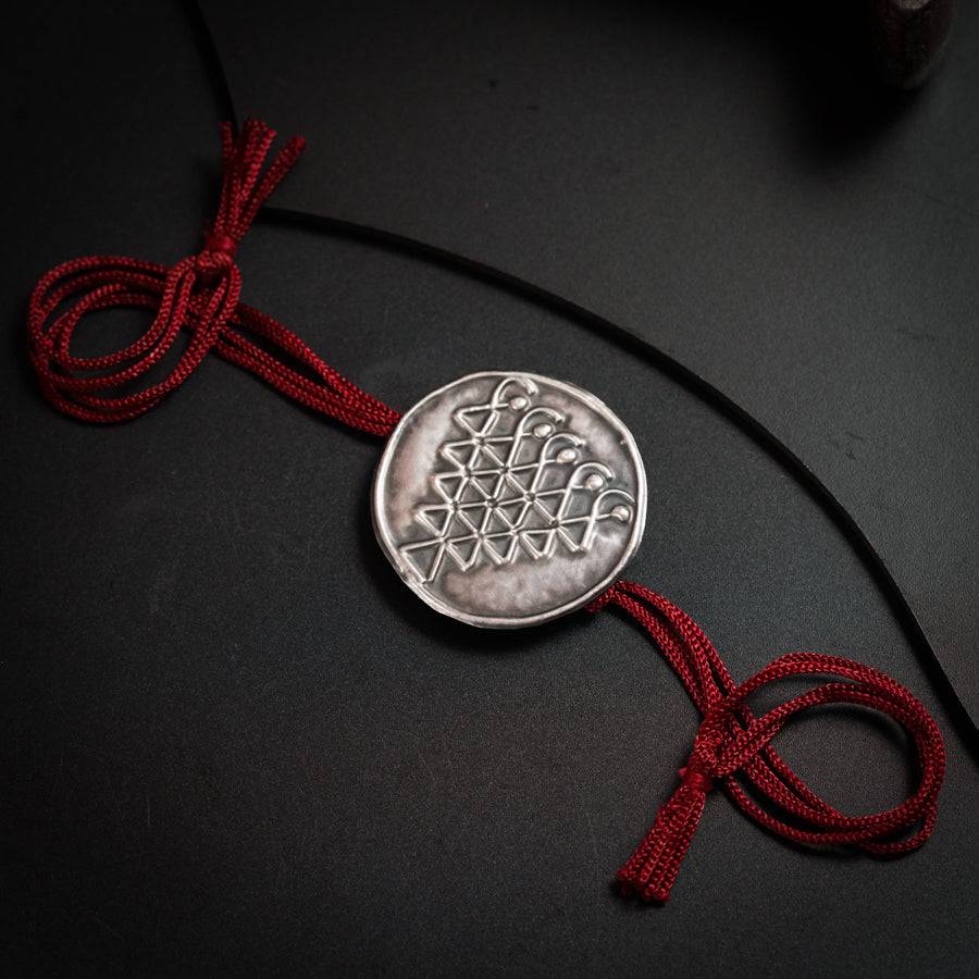 a silver coin with a red string on a black surface
