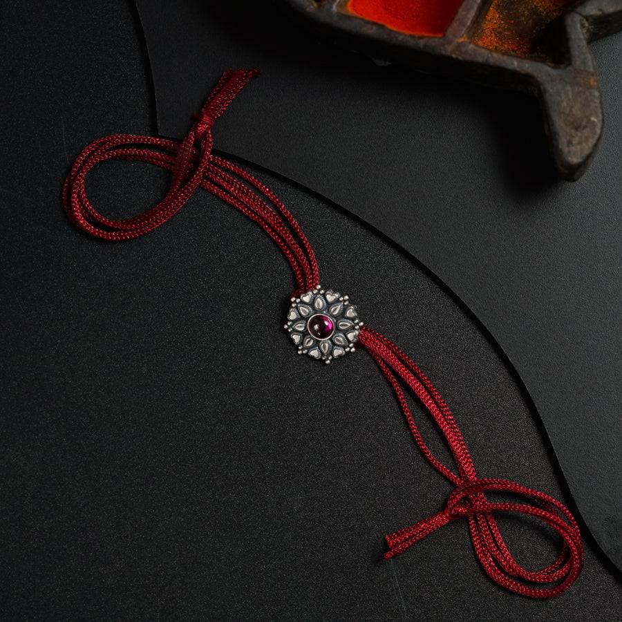 a red string with a flower brooch attached to it