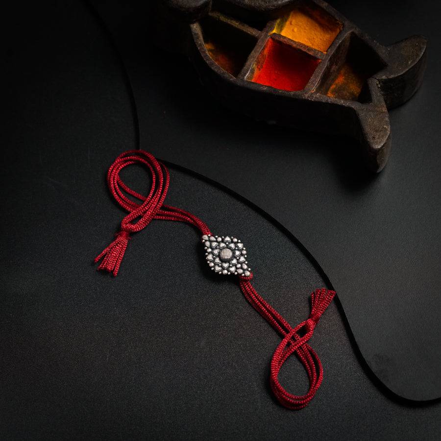 a red string with a silver bead on it