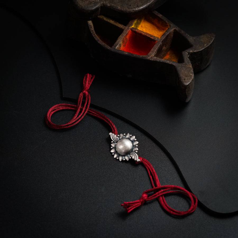 a red string with a silver bead on it