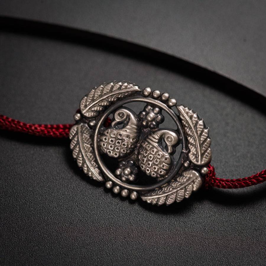 a silver bracelet with two owls on a red cord