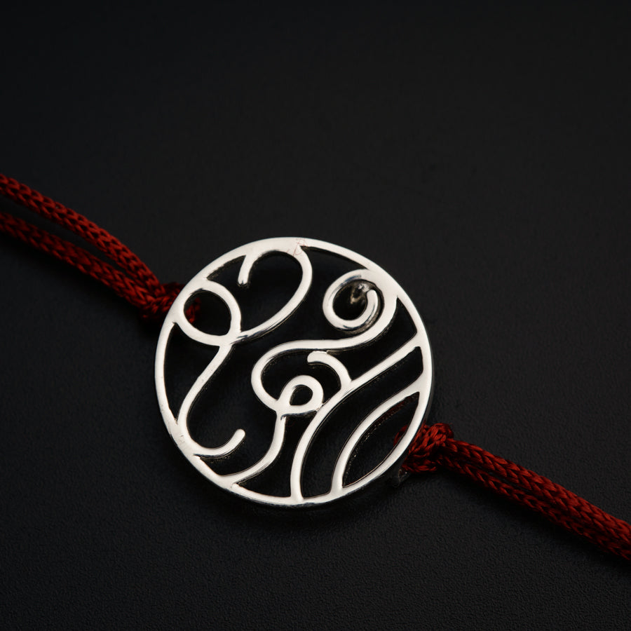 a silver pendant on a red string